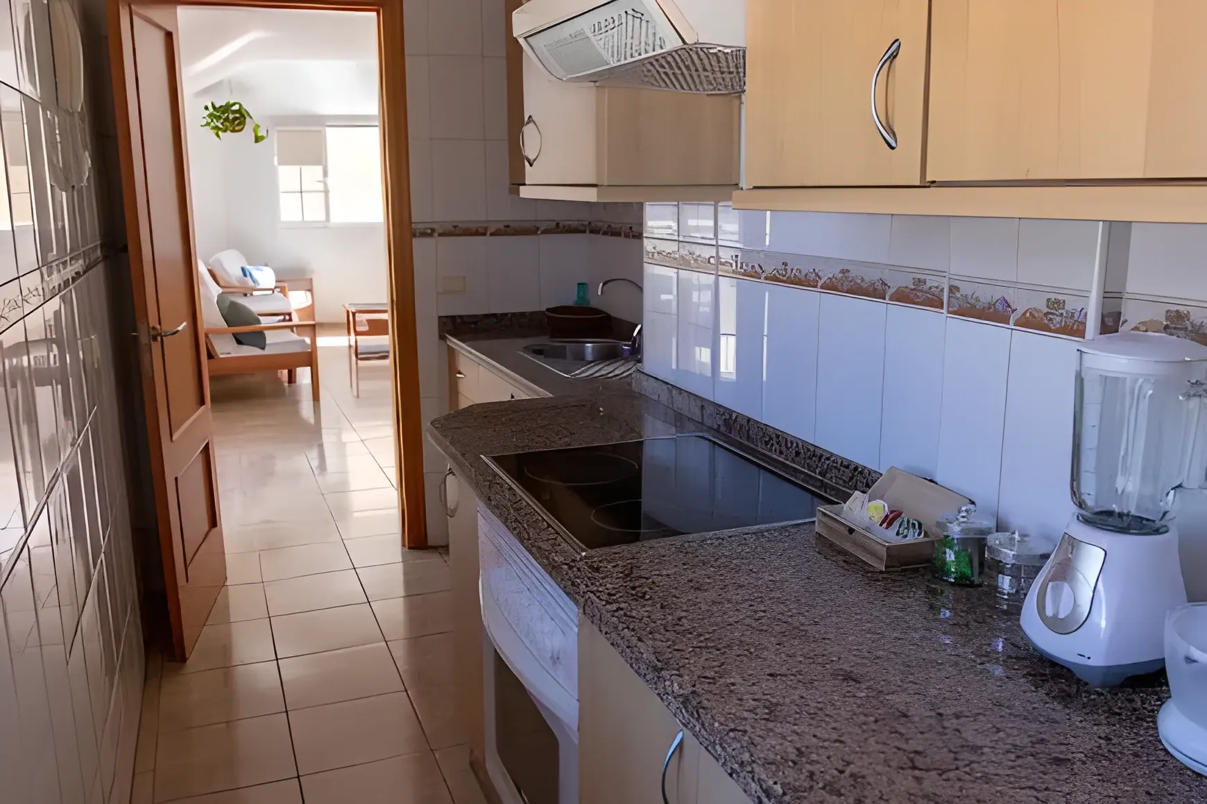 Cocina en L con encimera de granito, vitrocerámica y horno