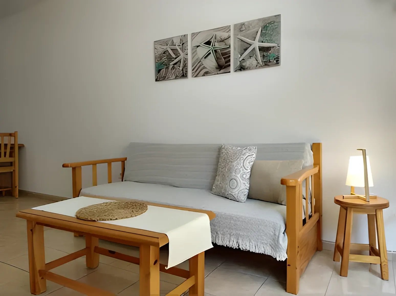 Salón con sofá de madera y cuadros marinos