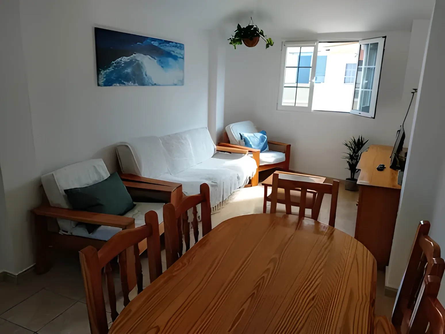 Salón-comedor con cuadro de una ola y mesa de madera