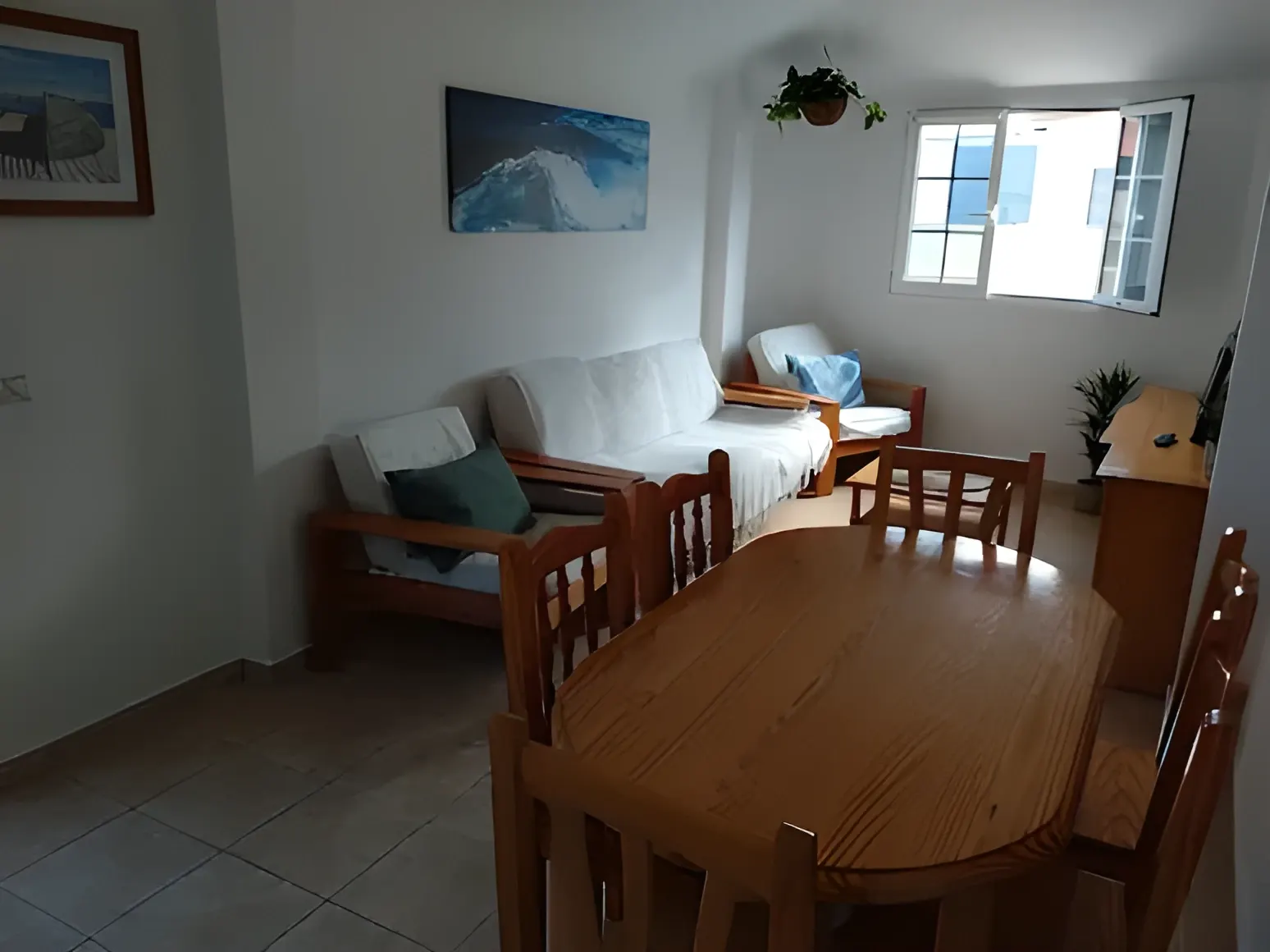 Salón-comedor con sofás blancos y ventana al pueblo