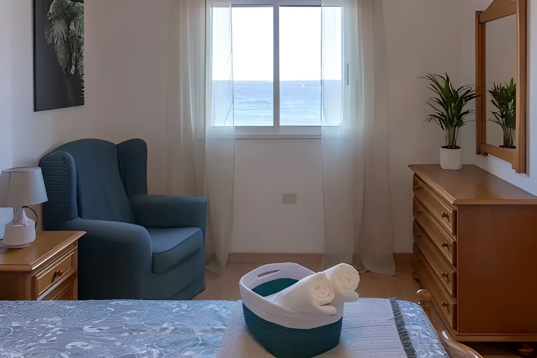 Dormitorio con butaca y ventana con vistas al mar