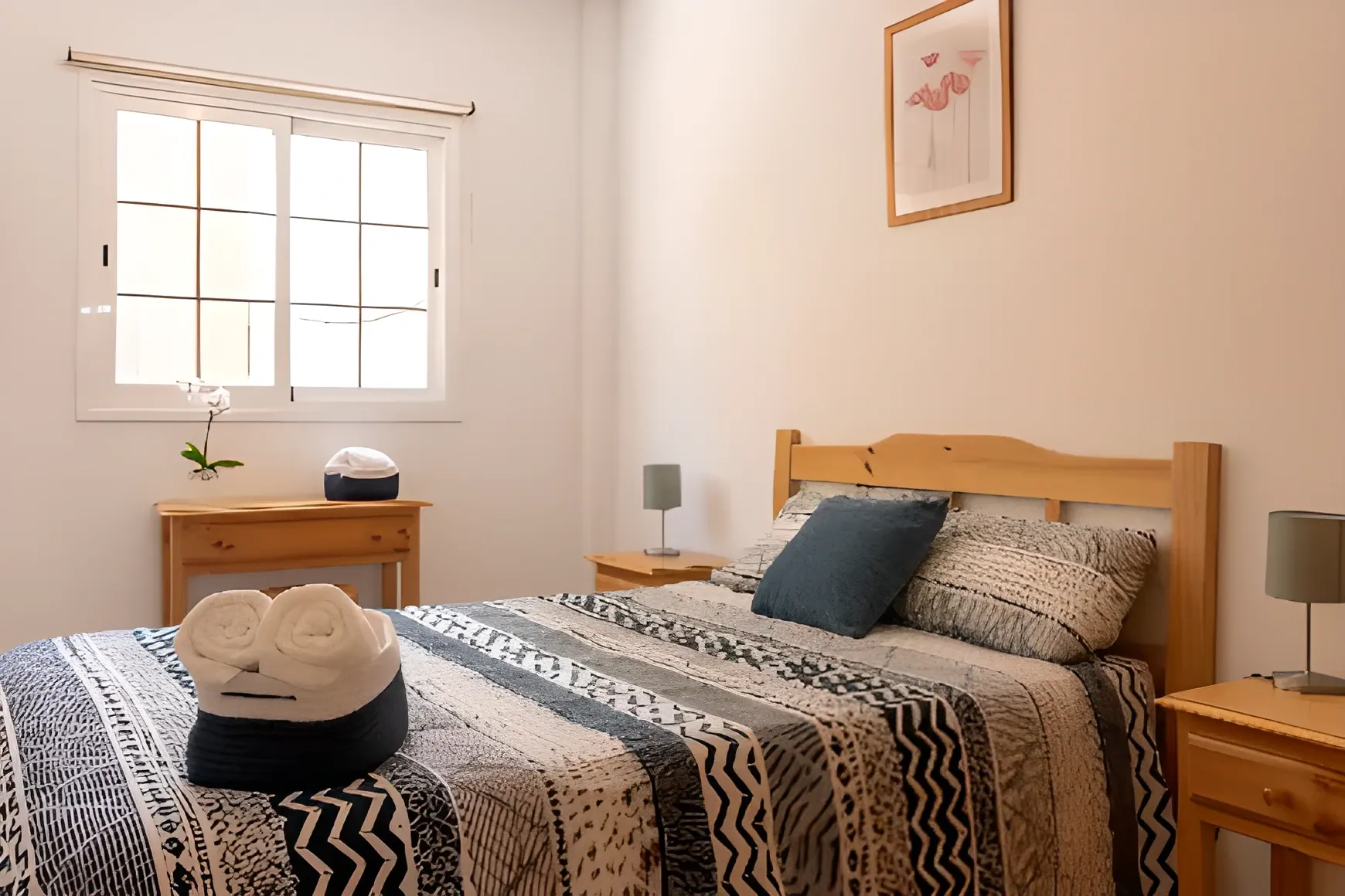 Dormitorio de matrimonio con cabecero de madera y toallas preparadas